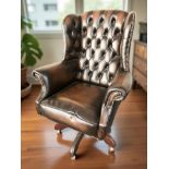 A contemporary Chesterfield deep button tan leather wing back swivel armchair,