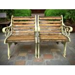 A pair of painted cast iron-framed garden armchairs, each 63 cm wide.