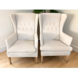 A pair of Scandinavian wing back armchairs in cream fabric