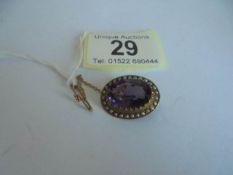 A Victorian amethyst and seed pearl brooch in a 9ct gold mount with safety chain.