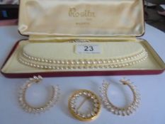 A two strand pearl necklace together with a sparkly brooch and earrings.