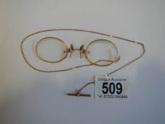 A pair of Pince Nez marked V10-12k with attached chain, in good condition.