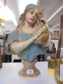 A plaster bust of a female with a string instrument.