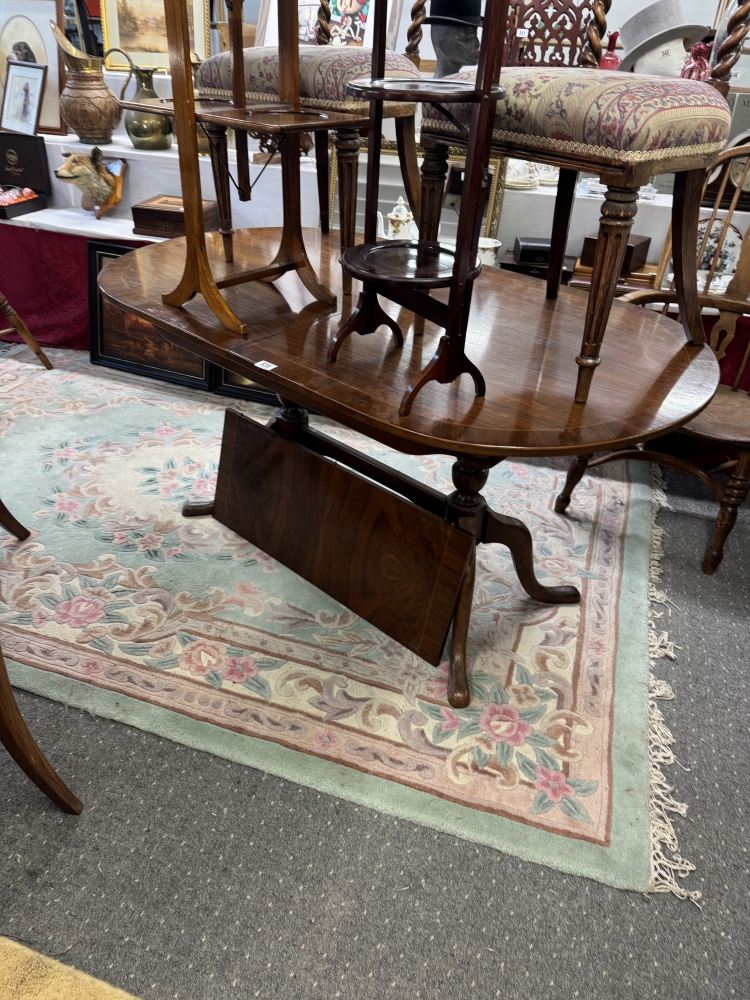 An oval extending string inlaid dining table.