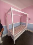 A wood-framed four-poster single bed