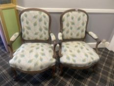 A pair of wood-framed armchairs with peacock fabric