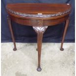 Mahogany demi lune fold over card table, the top having carved edge opening to reveal brown felt