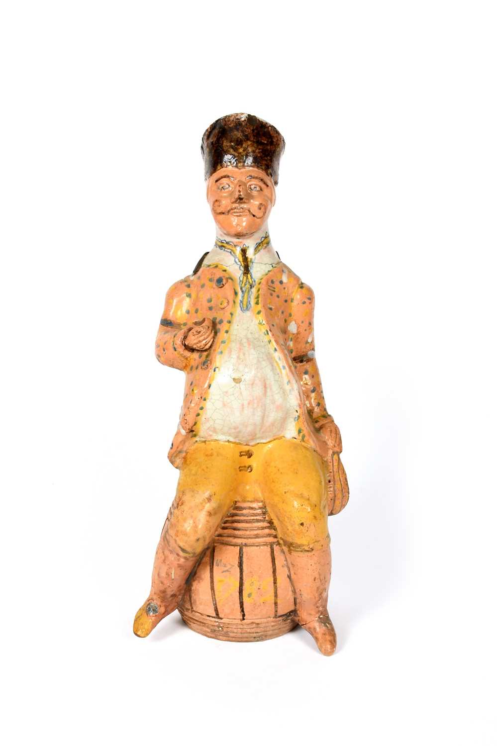 A Rouen faïence figural jug, dated 1782, modelled as a corpulent figure in a tall hat, seated on