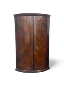 A George II walnut, crossbanded and featherbanded bowfront corner cupboard