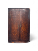 An unusual George III burr oak and crossbanded bowfront hanging corner cupboard