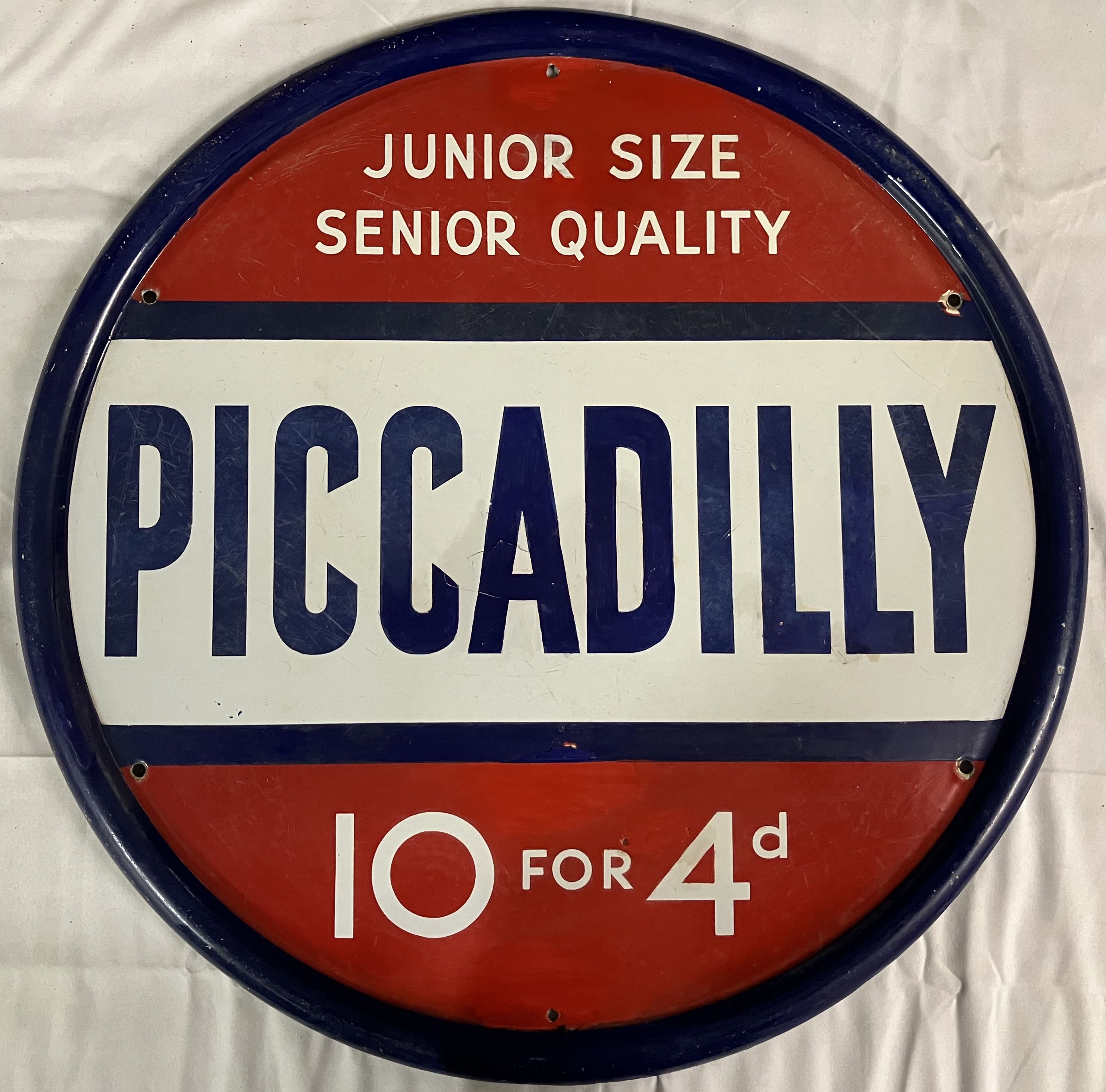 An enamel circular advertising sign for Piccadilly Cigarettes that appears to have had some