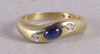 Een 14 krt geelgouden designring, bezet met cabochongeslepen saffier en briljant