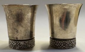A pair of silver beakers.