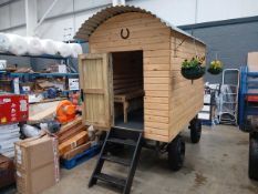 Small, newly-constructed wooden shepherd's hut on a twin-axle chassis with rear leaf springs,