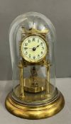 A German Lorsion clock supported on two brass pillars with a glass dome