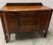 An oak sideboard with drawers to centre flanked by cupboards (H105cm
