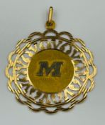 An 18ct gold pendant with the letter M, approximate weight 7.7g, approximate 40mm diameter.