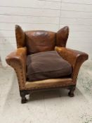 A brown leather upholstered club chair with brass stud detail