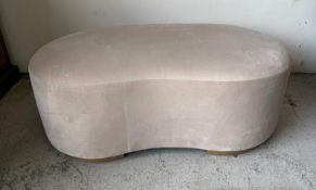 A beige kidney shape foot stall or pouffee