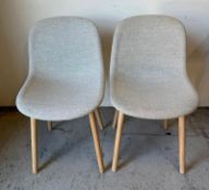 A pair of pale grey dining chairs on wooden legs