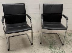 A pair of chrome and faux black leather dining chairs