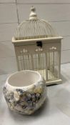 A cream decorative bird cage along with a ceramic plan pot