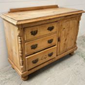 A pine side cabinet with three drawers and one panelled door opening to shelves (W121cm D51cm