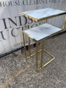 A two tier side table on metal legs with faux marble tops