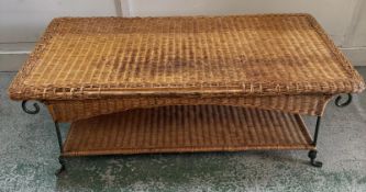 A wrought iron and wicker coffee table, with a woven top and lower shelf for storage. (H42cm