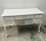A white painted desk on turned legs with central drawer and two drawers either side (120cm x 50cm