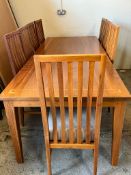 A cherry wood dining table with a geometric inlaid border and ten chairs