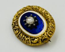 An antique diamond and blue enamel brooch 34mm in length with central diamond.