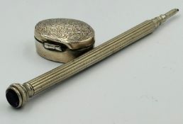 A silver pill box and pencil