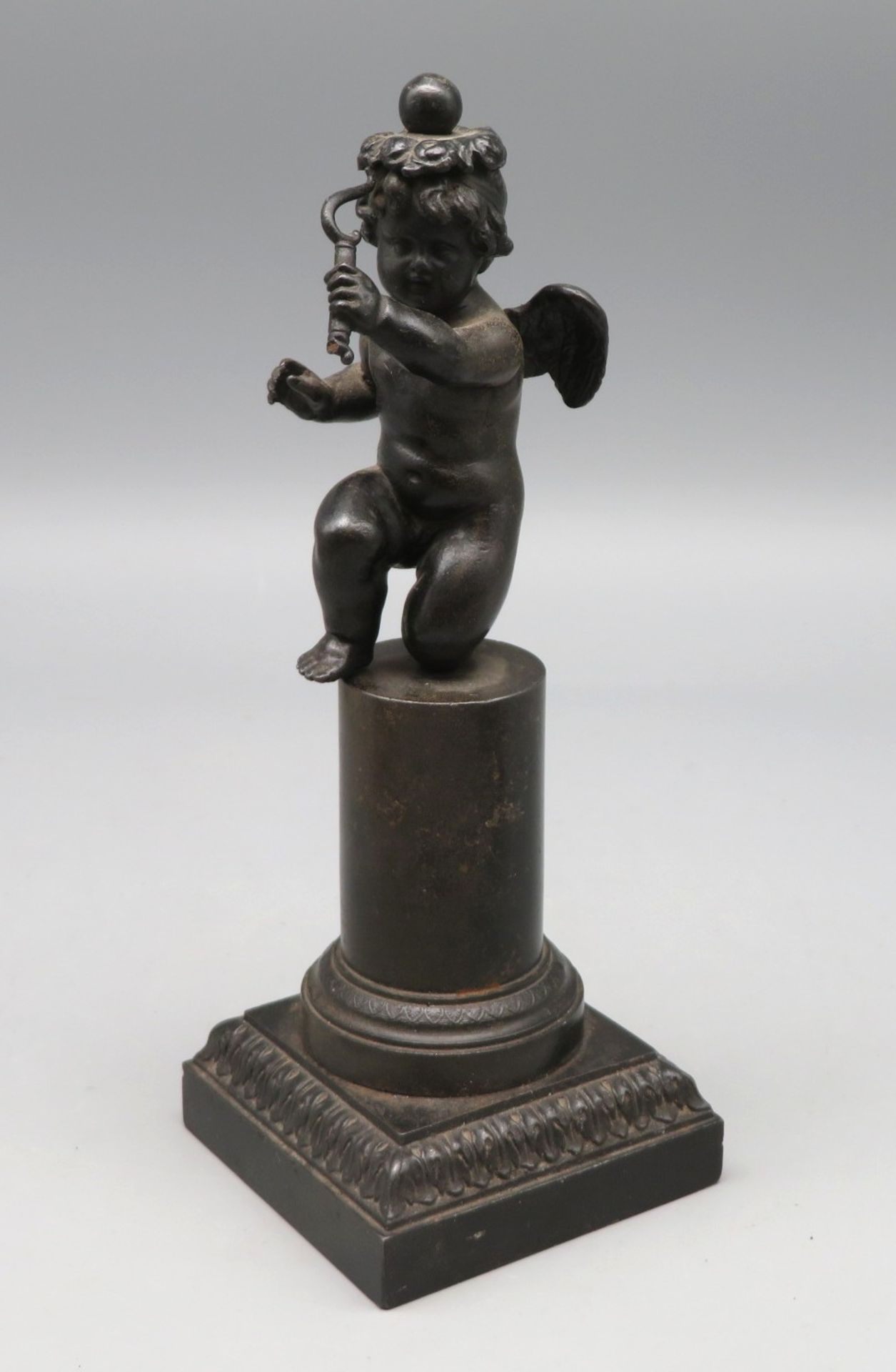 Amor/Amorette auf Säule, 18./19. Jahrhundert, Eisenguss, Bogen besch., 18 x 7 x 7 cm.