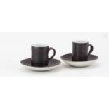 † LUCIE RIE (1902-1995); a near pair of stoneware cups and saucers covered in manganese and white