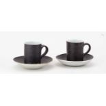 † LUCIE RIE (1902-1995); a near pair of stoneware cups and saucers covered in manganese and white