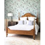 A walnut four poster style bed, with four turned large uprights, with serpentine panelled headboard,