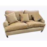 GEORGE SMITH; a modern two seater sofa, golden upholstery, on turned legs with fitted castors,