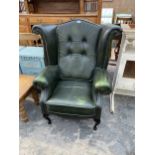 A GREEN LEATHER WINGED EASY CHAIR ON FRONT CABRIOLE LEGS