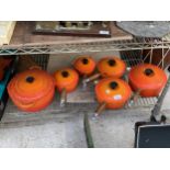 A SET OF FIVE ORANGE GRADUATED LE CREUSET SAUCEPANS AND A CASAROLE DISH