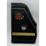 A vintage Gitarr Zither stringed musical instrument of German origin which features a black