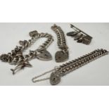 Three silver charm bracelets with heart shaped padlock fastenings and some loose charms; the charm