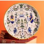An Italian maiolica circular charger, painted in polychrome, with armorials, mythical figures and