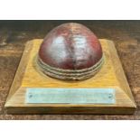 Sport and Curiosities - a bisected cricket ball, mounted for the desk, the oak base with
