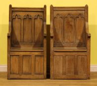 A pair of Gothic Revival design oak panel back box seat armchairs, the architectural back carved