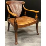 An Arts and Crafts oak armchair with shaped top rail over shield shaped leather back, flanked by