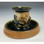 A Doulton Lambeth candlestick holder, modelled as a Toby by Harry Simeon titled 'The best is not too