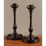 A pair of 19th century turned mahogany table candlesticks, brass sconces and drip pans, baluster