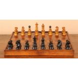 An early 20th century chess set, the folding fruitwood chessboard containing lacquered and