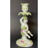 A Derby patch mark figural candlestick, as putto, draped in fruiting vine, seated on a stump,